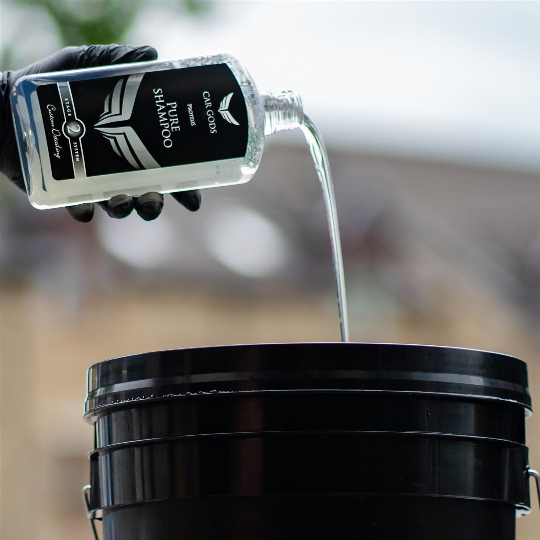 Pouring car shampoo into a detailing bucket