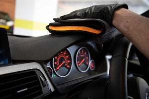 Cleaning car dashboard with a microfibre cloth