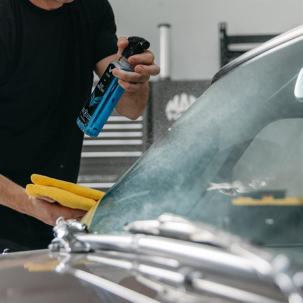 glass cleaner being sprayed onto a car windshield