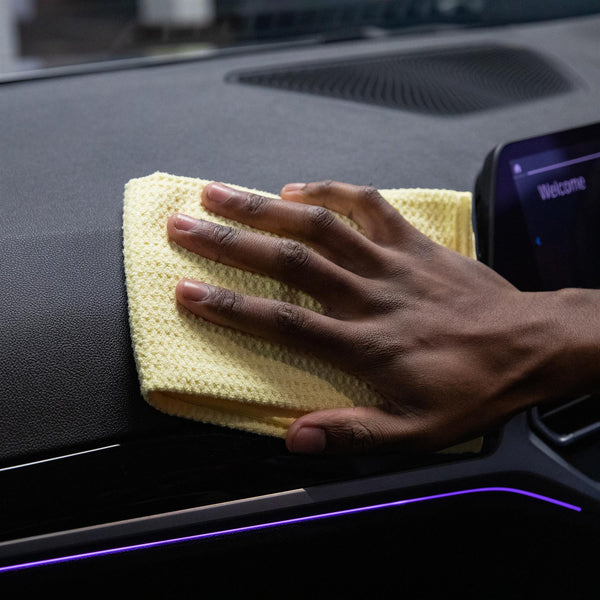 Microfibre cloth being used to dry the interior dashboard of a car
