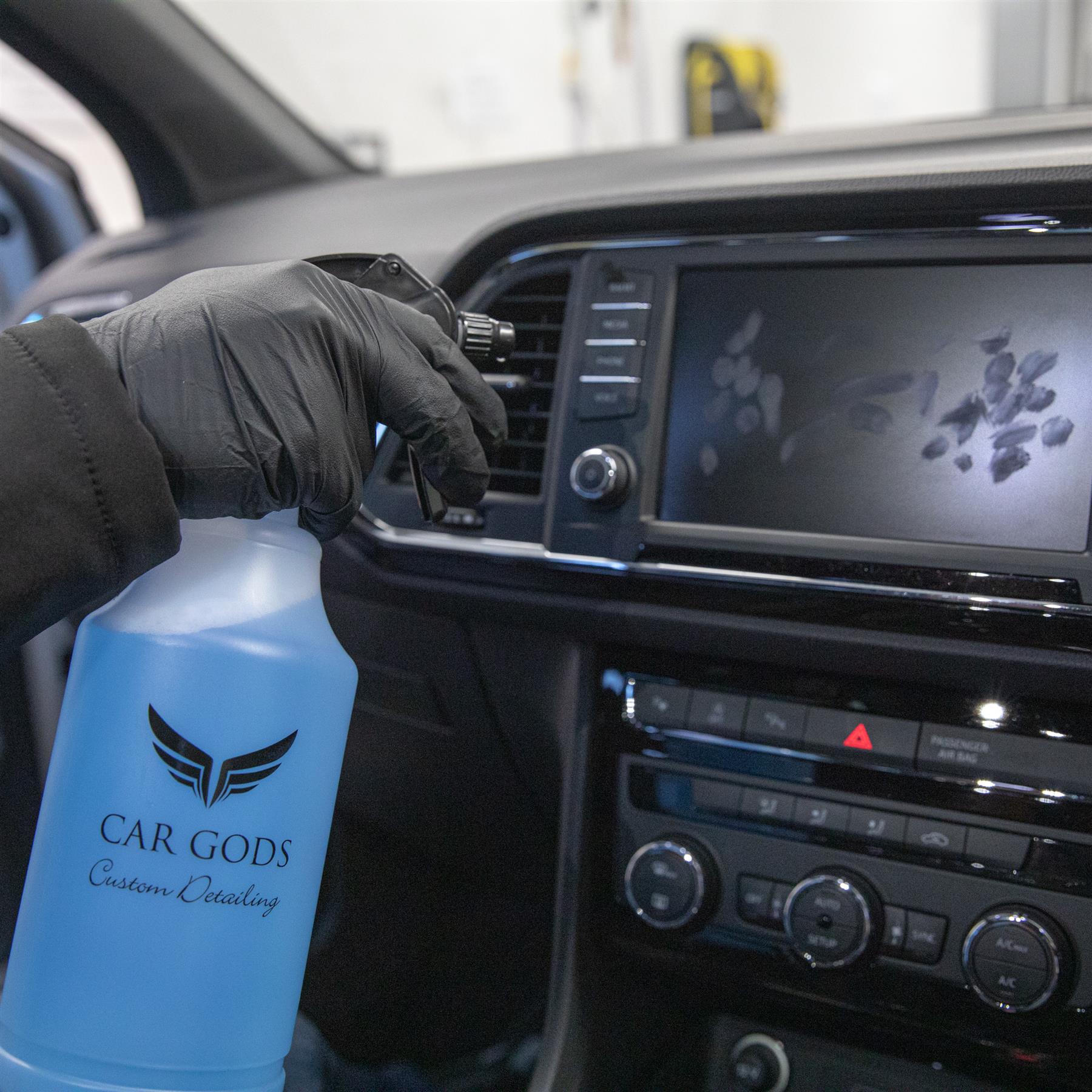 Spraying glass perfection cleaner onto infotainment screen